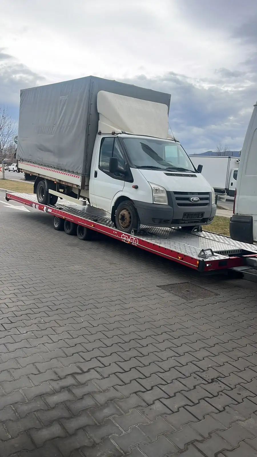 Ford Transit cu prelată încărcat pe trailer
