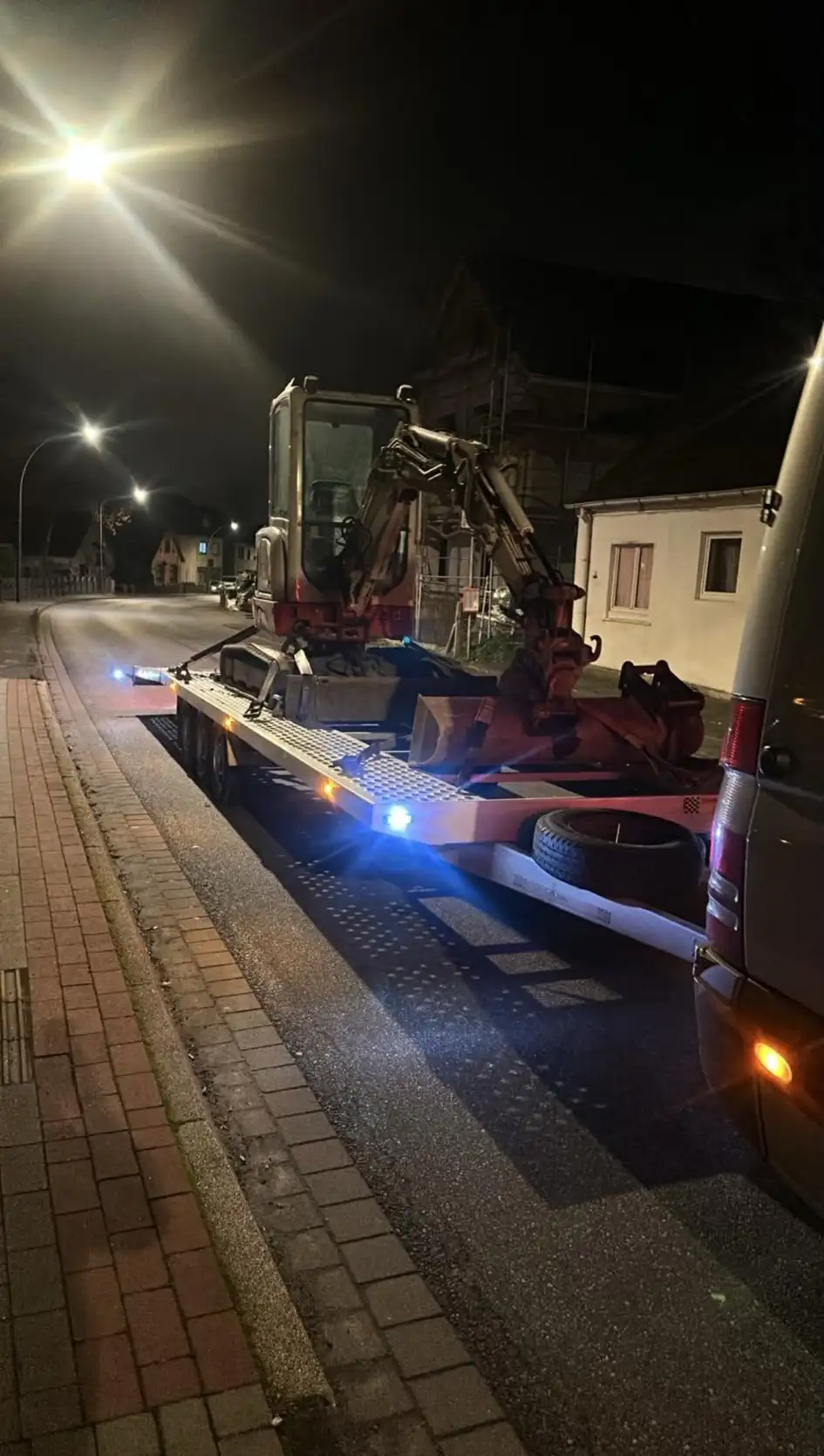 Miniexcavator încărcat pe trailer, noaptea, în Germania